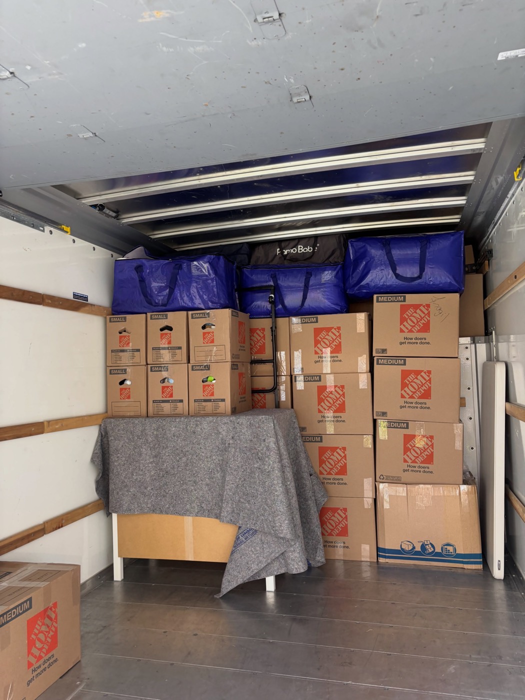 Interior of a loaded moving truck with furniture under moving blankets and boxes stacked by size